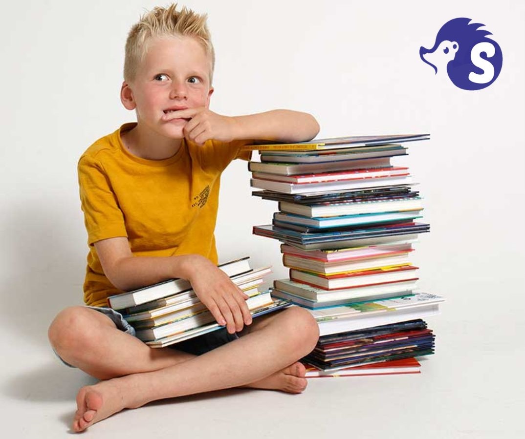 Jongen kijkt bedenkelijk met stapel boeken naast zich